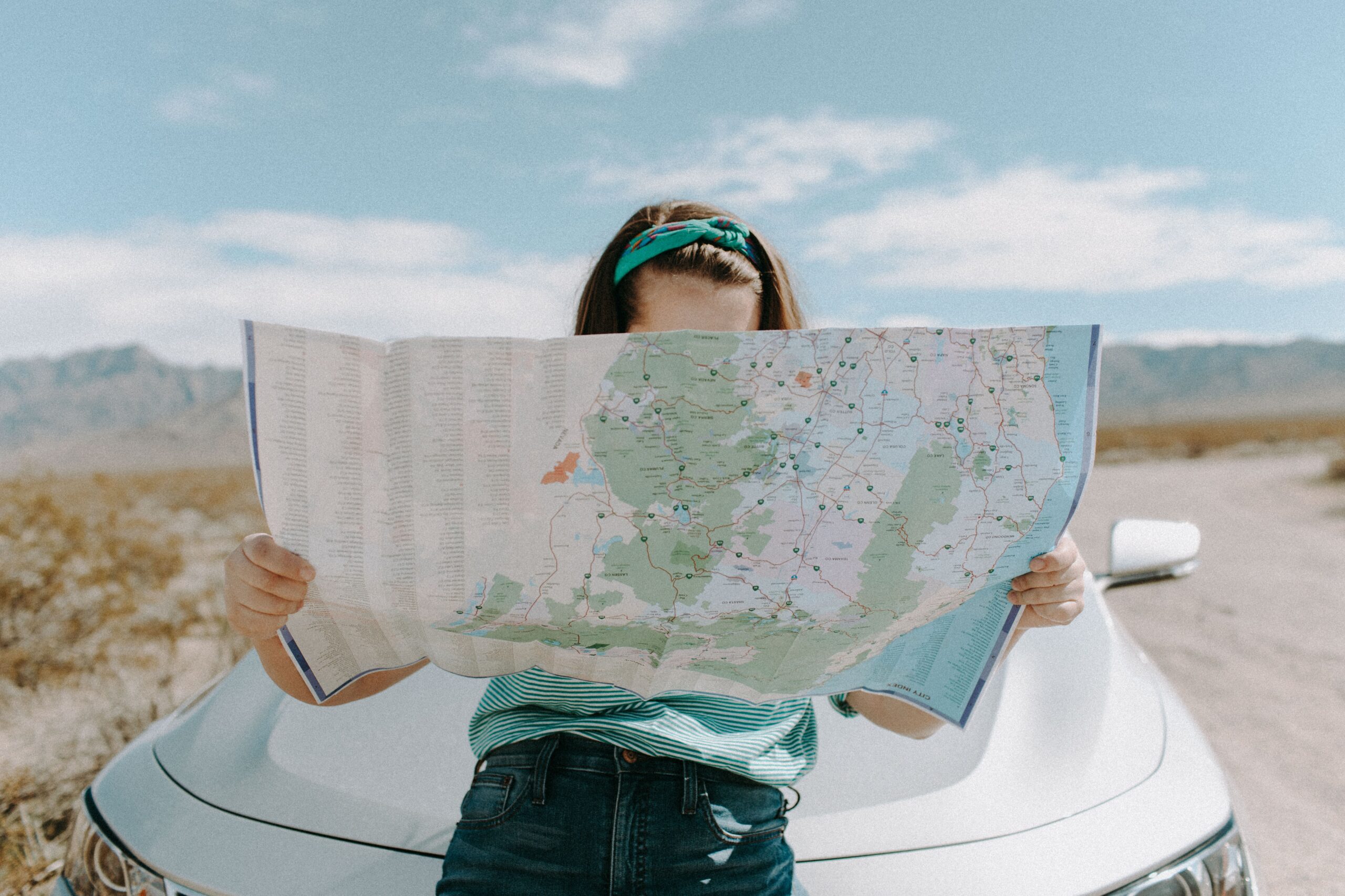 woman looking at map perched on a car