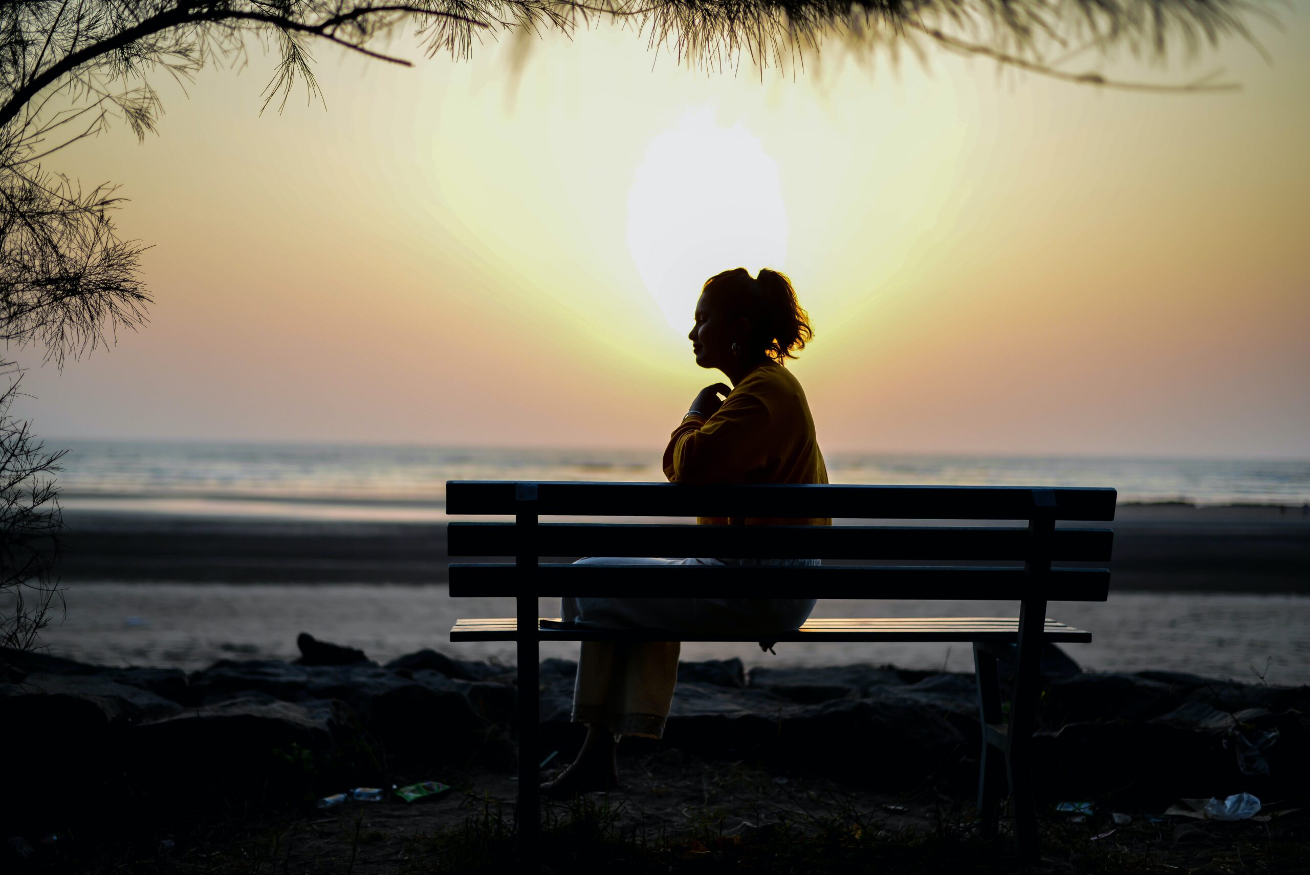 woman sitting alone in front of the sunset