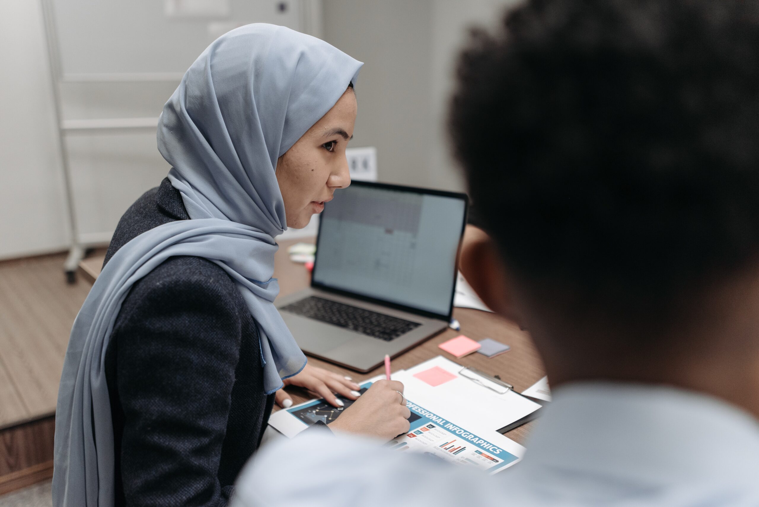 woman in gray hijab sitting behind an office table