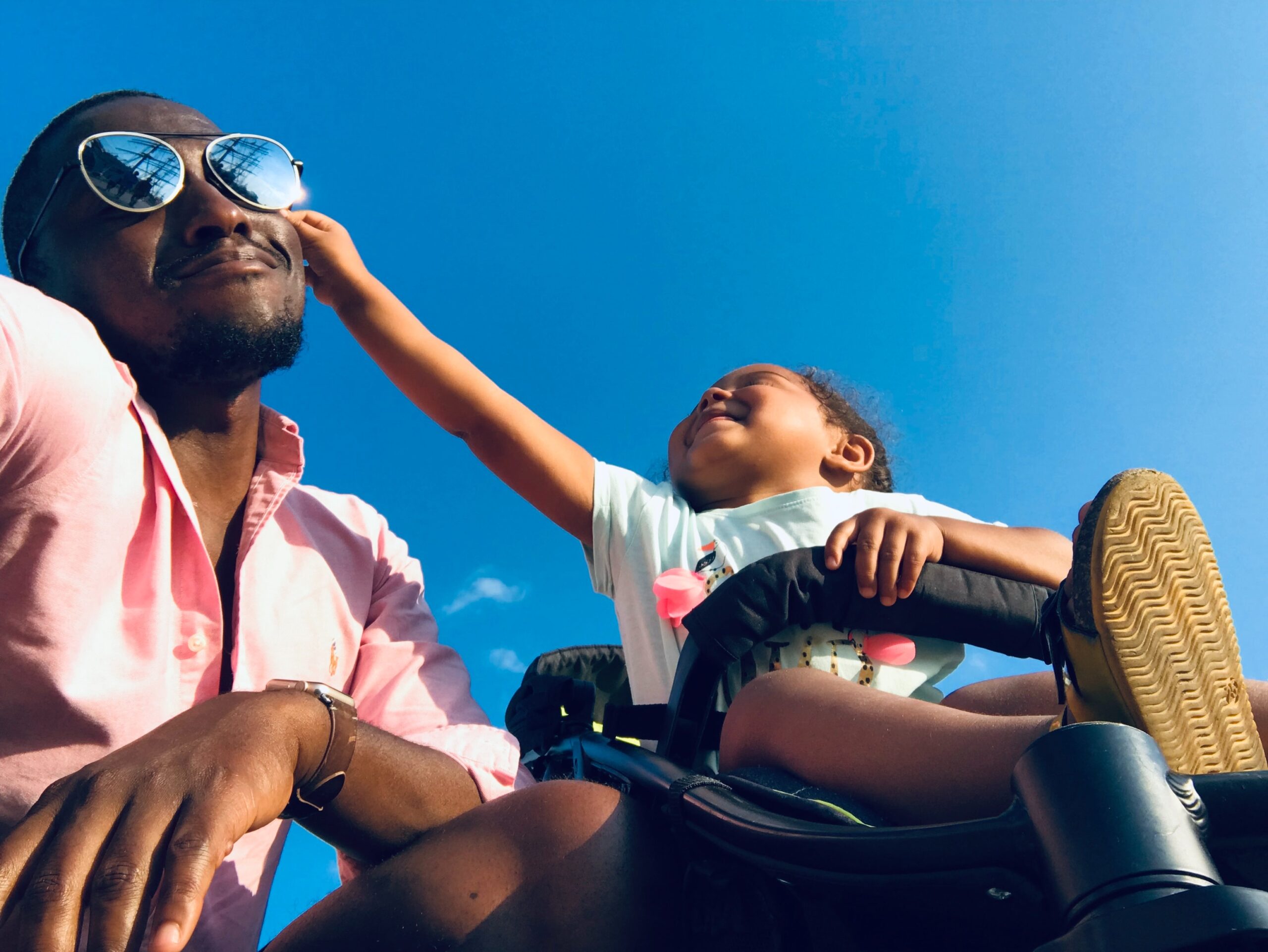 black child reaching for sunglasses on their father's face