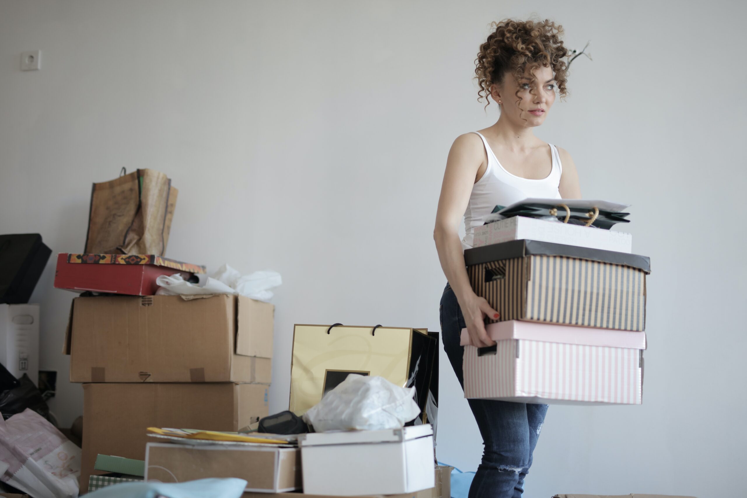 concentrated woman carrying stack of cardboard boxes for relocation