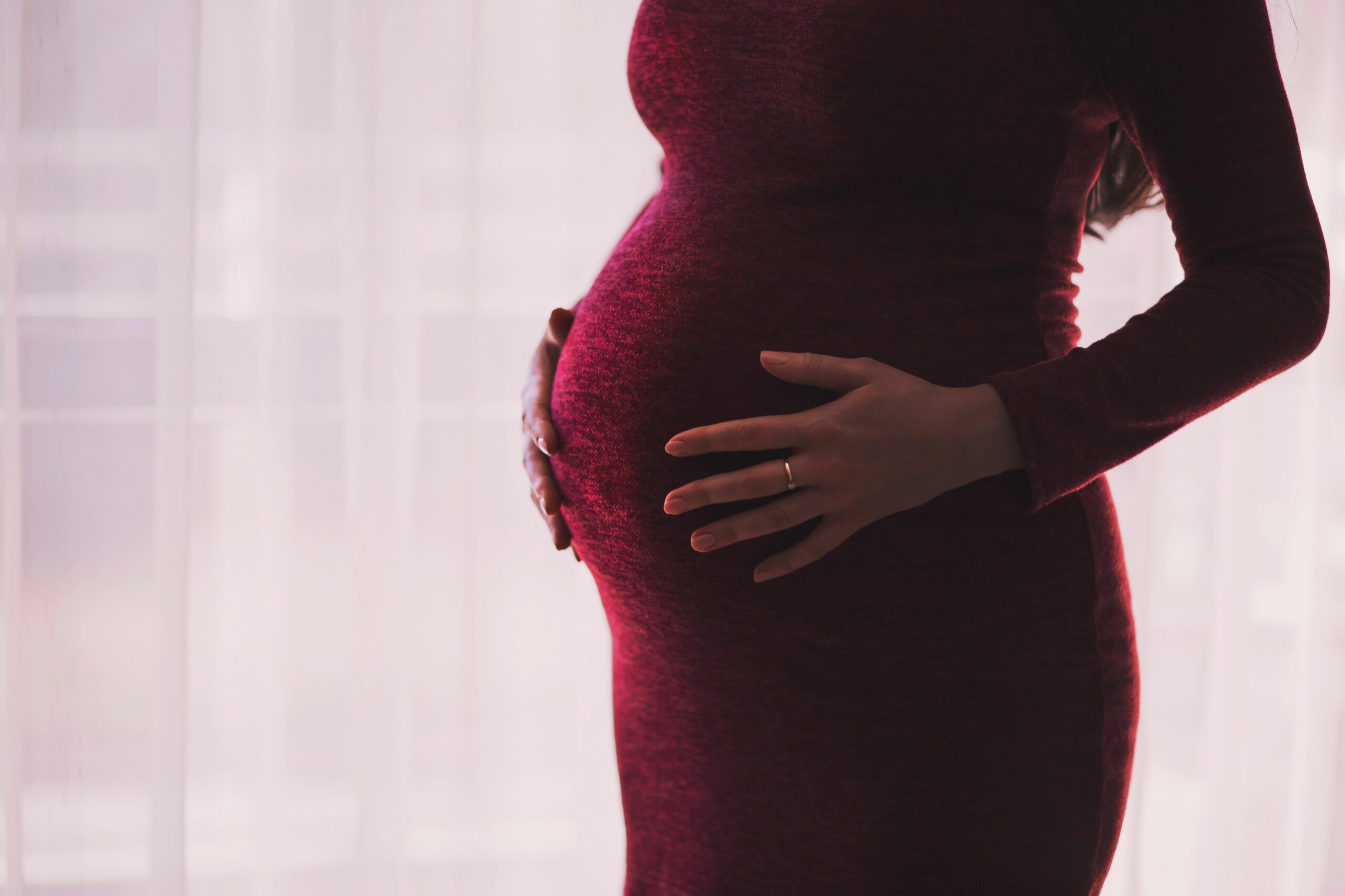 pregnant woman in red dress holding belly