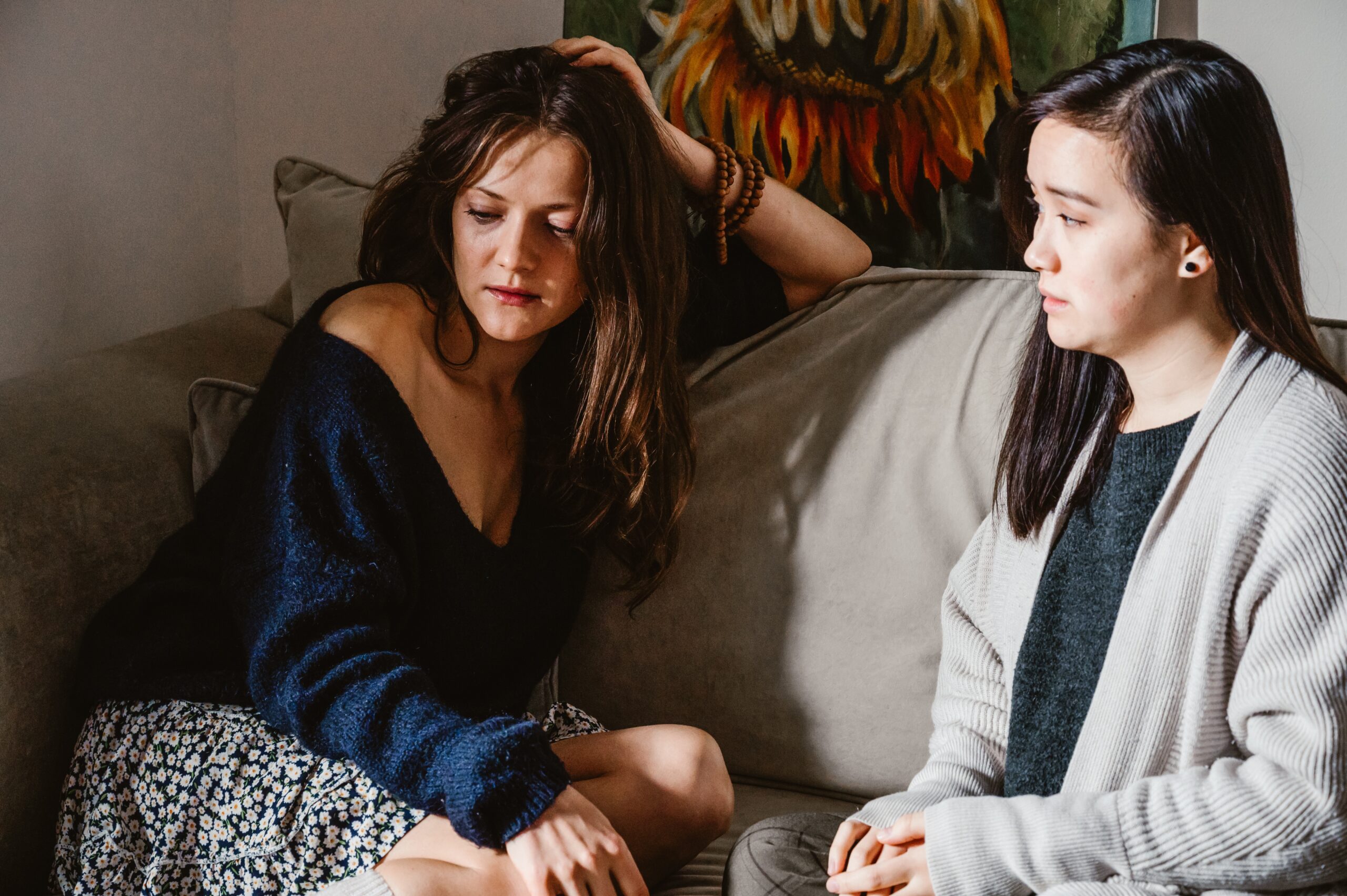 two sad women sitting on couch