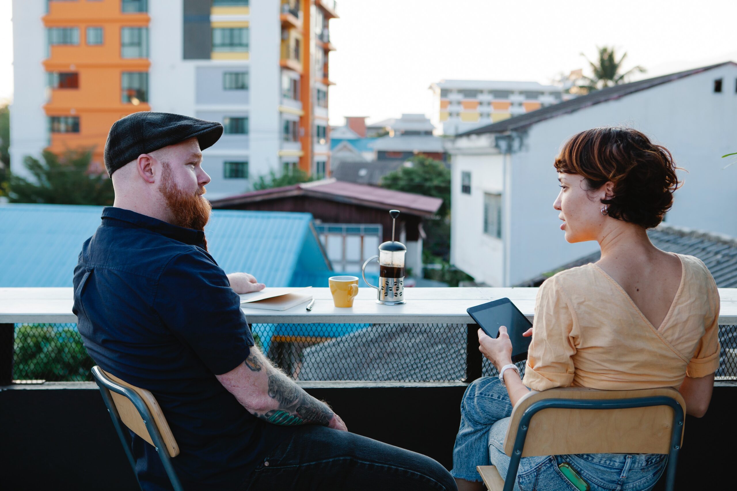 man and woman chatting on a terrace, drinking coffee