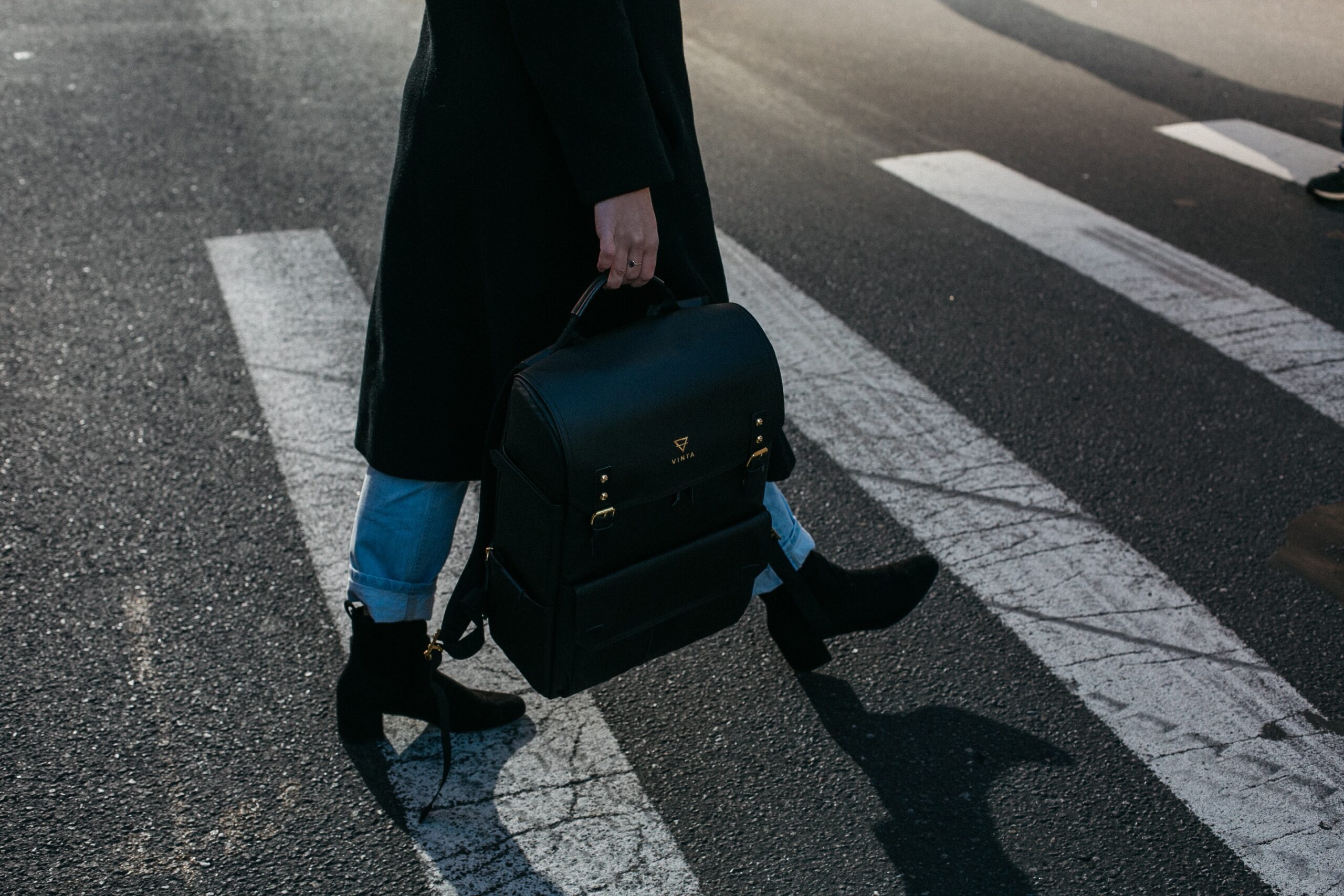 woman carrying a suitcase walking a crosswalk