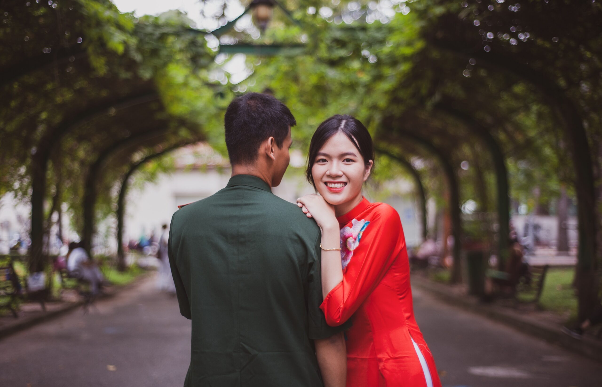 asian couple walking beneath trees in a park