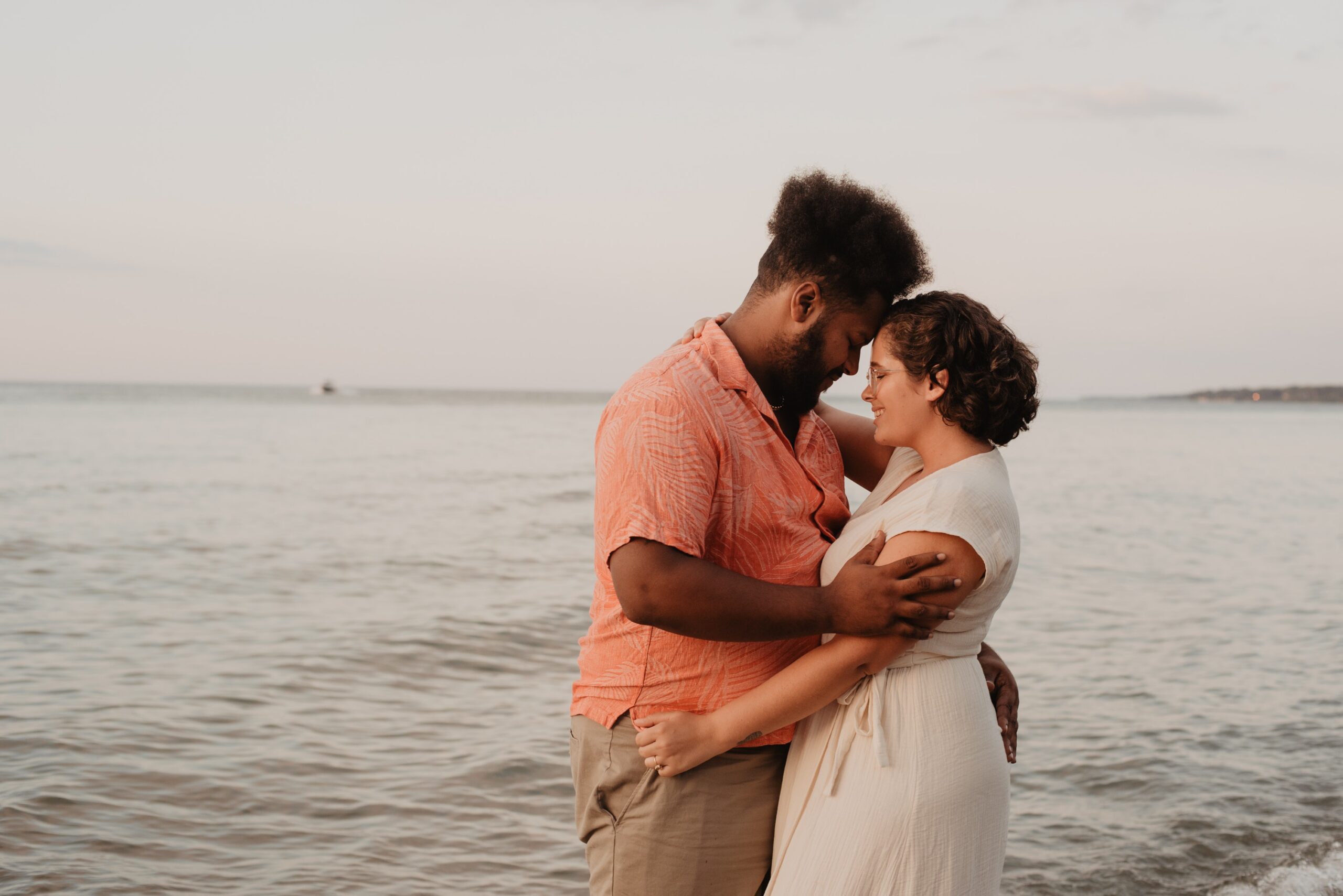 happy multiracial man and woman hugging in front of the ocean