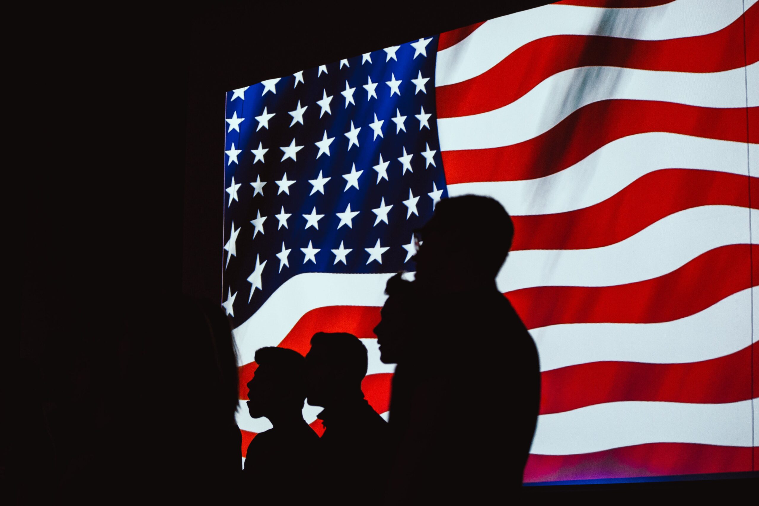 silhouettes of four people in front of US flag