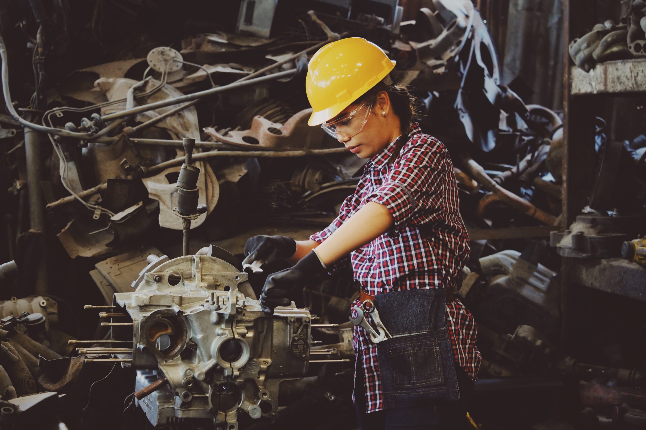 woman in yellow hardhat working on a car