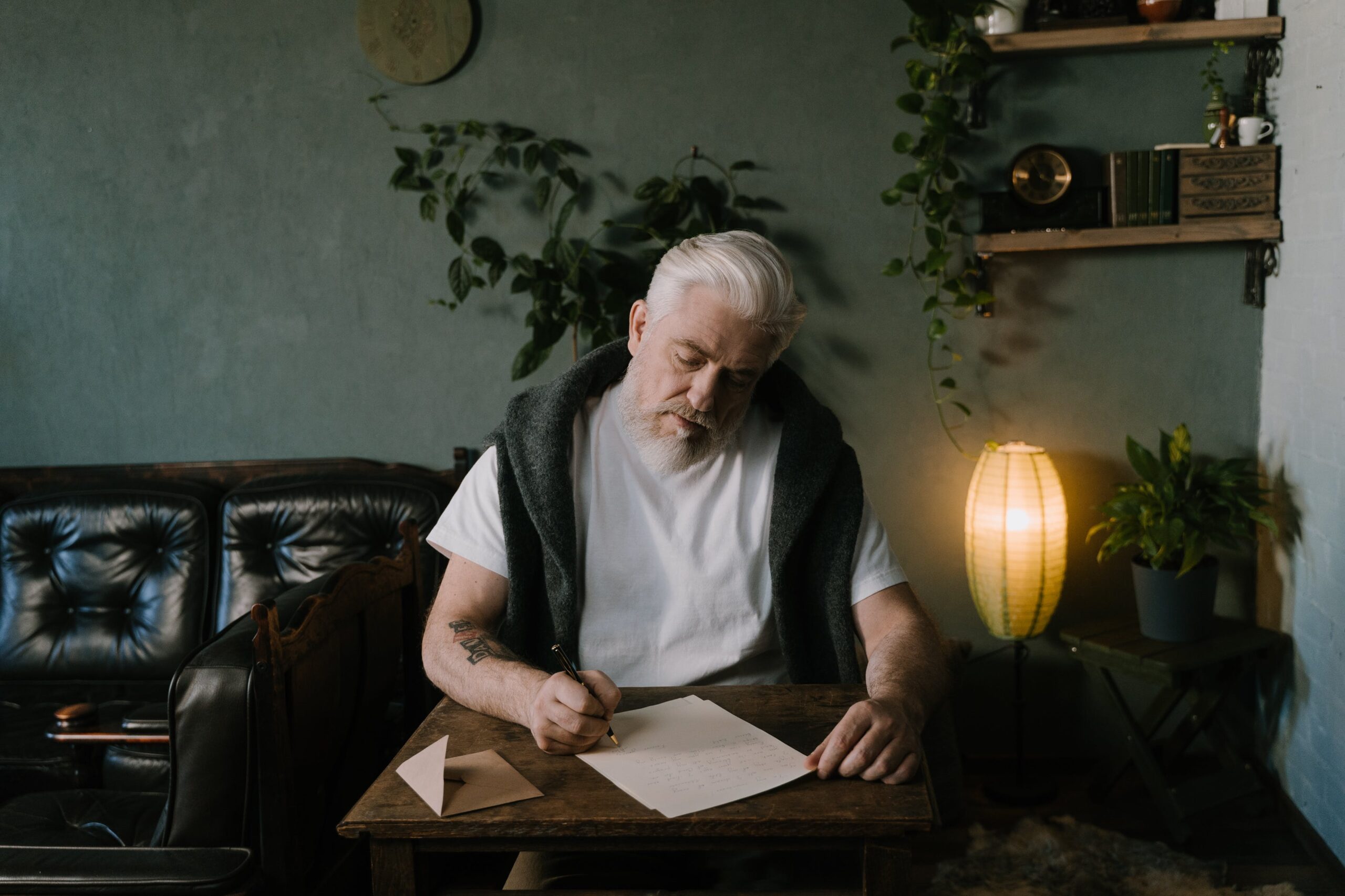 man with a beard sitting at a table writing a letter