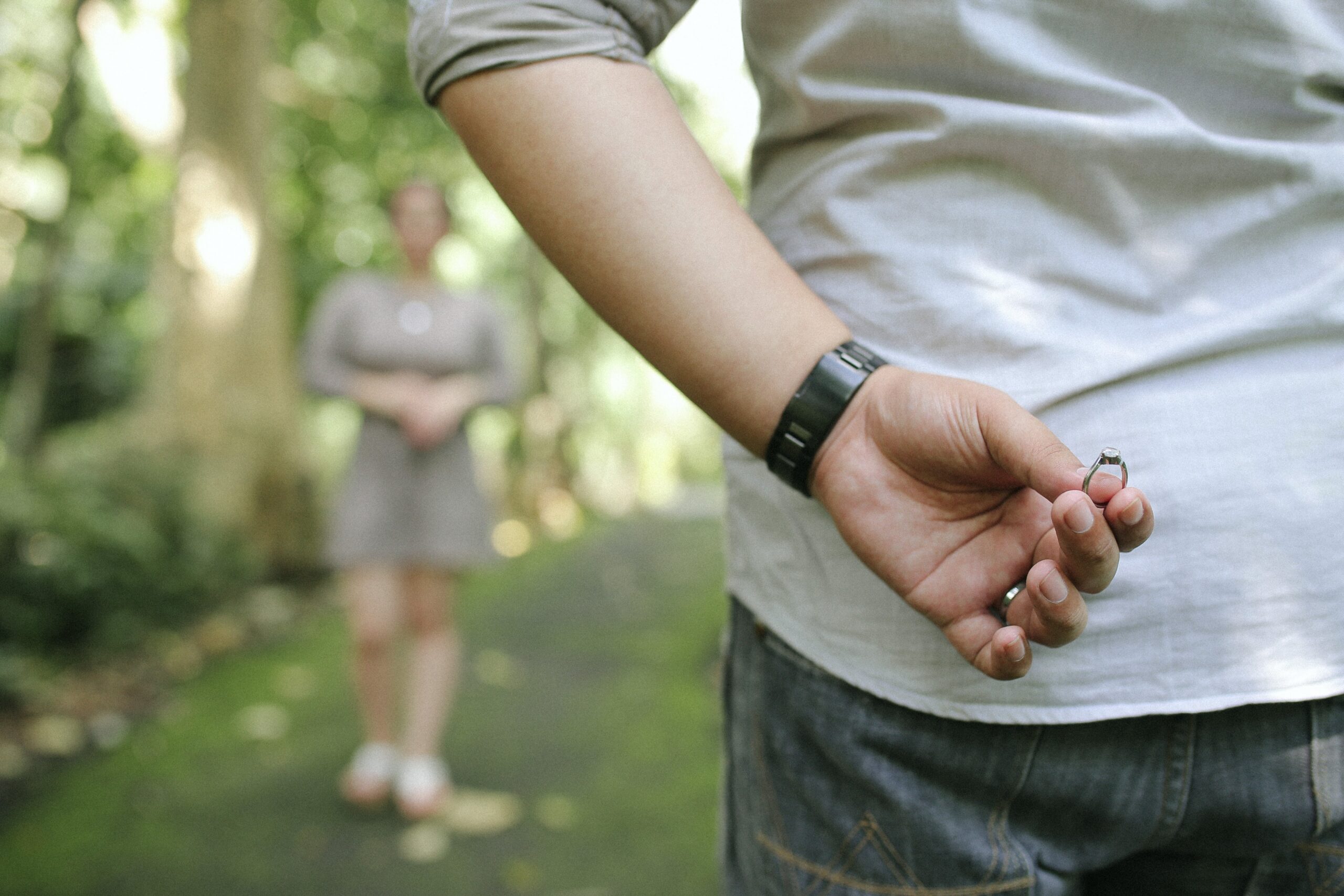 close-up of man holding ring behind his back about to propose