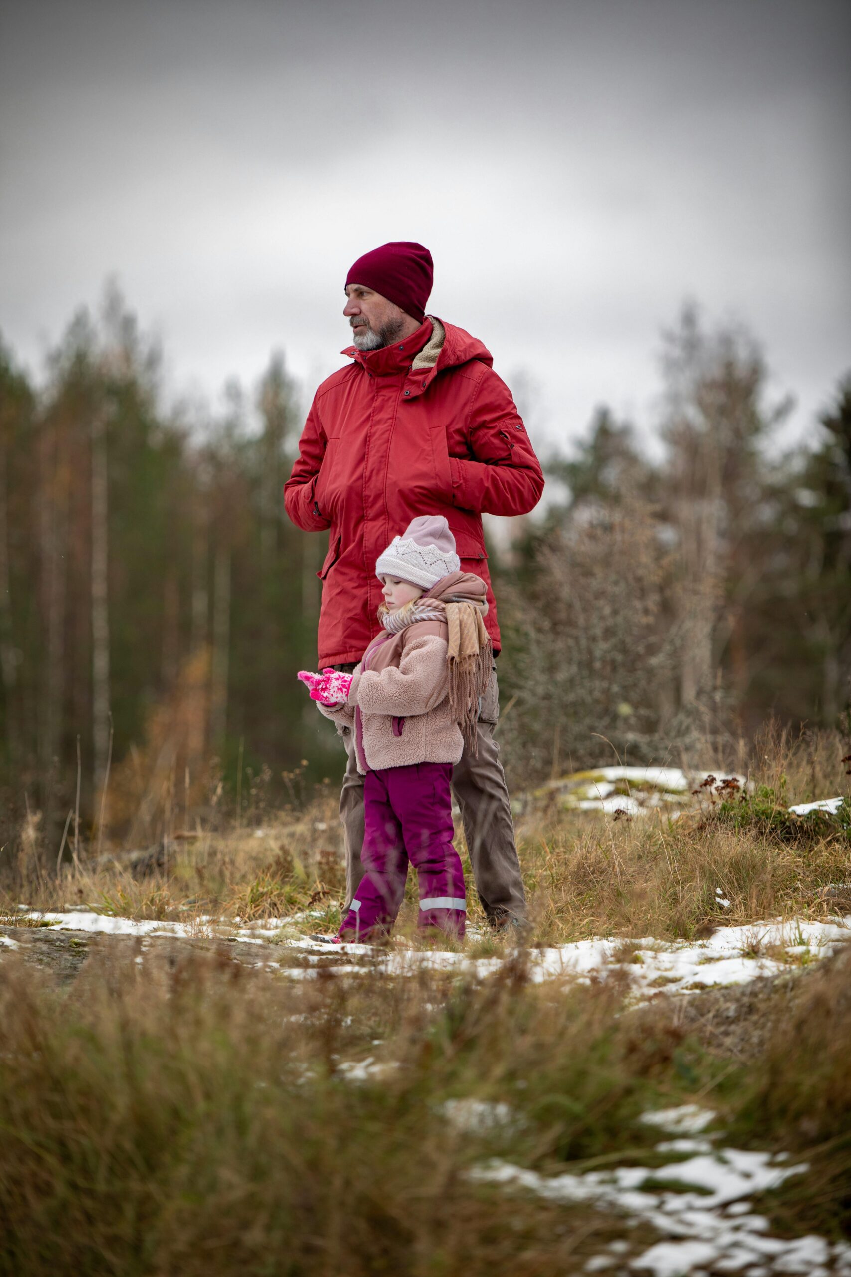 man walks next to daughter on a late winter or early spring day as snow is melting