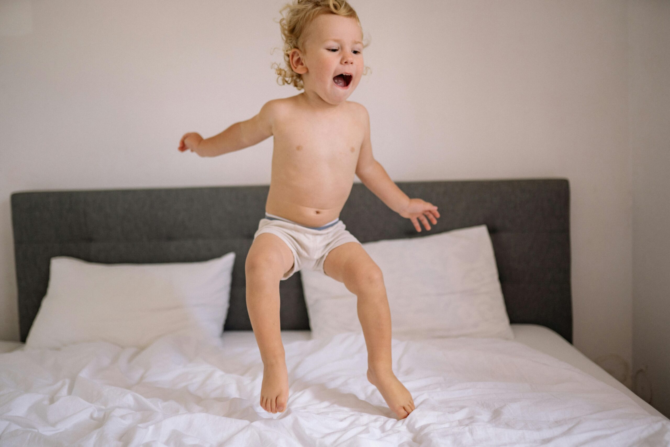 young boy jumping on a bed in his underwear